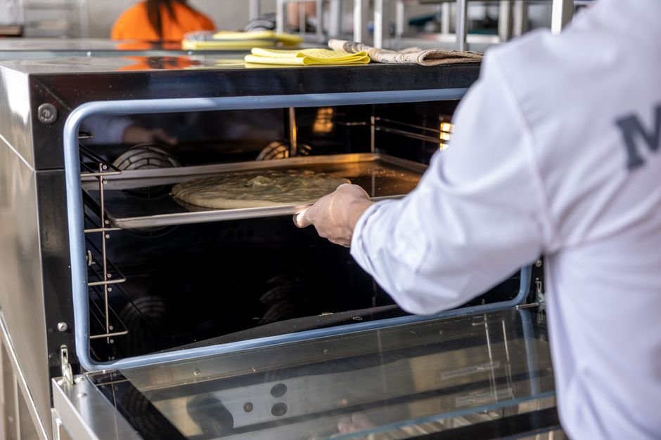 Un chef professionnel utilisant un four à pizza à gaz dans une cuisine moderne.